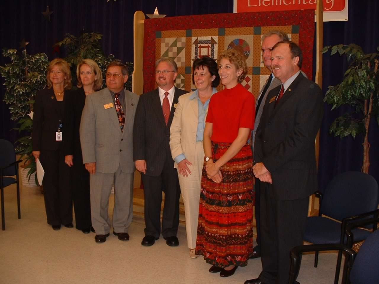 School officials posing in front of Underground Railroad quilt.